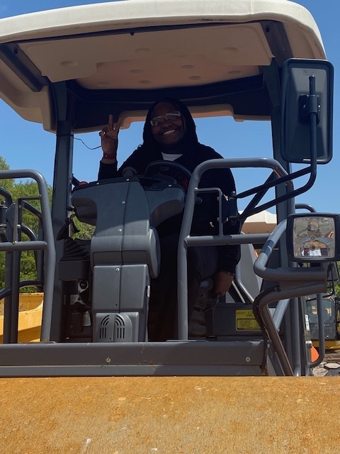 Student smiling as they sit in the cab of a piece of AIS equipment
