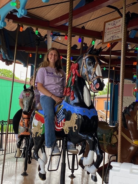 Female student riding the zoo carousel