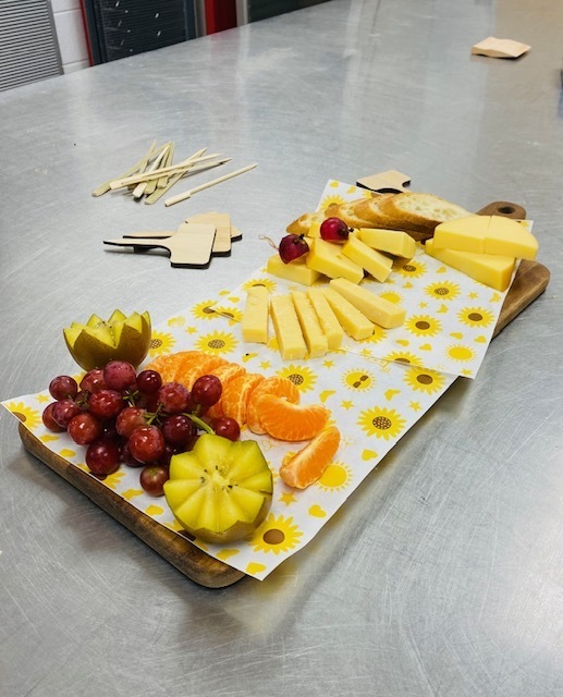 cheese and fruit tray with different cheeses, bread, grapes oranges and kiwi