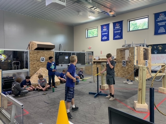 Group of students in a lab space holding a tape measuring and working on building a structure