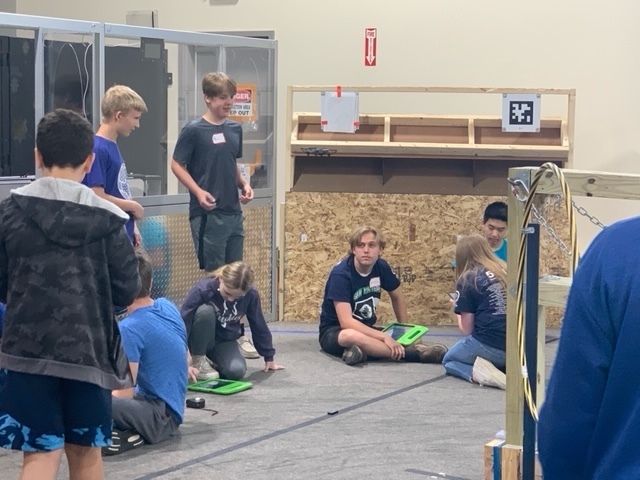 7 students in a group discussing the plans for their drone trials