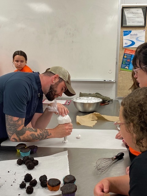 Chef Jake showing students how to use a frosting bag