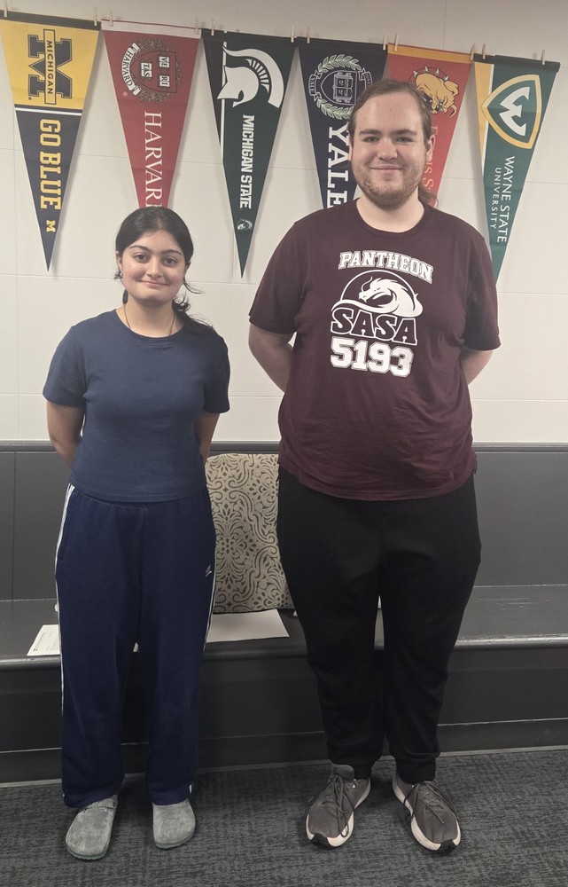 Two SASA students pose in front of college banners