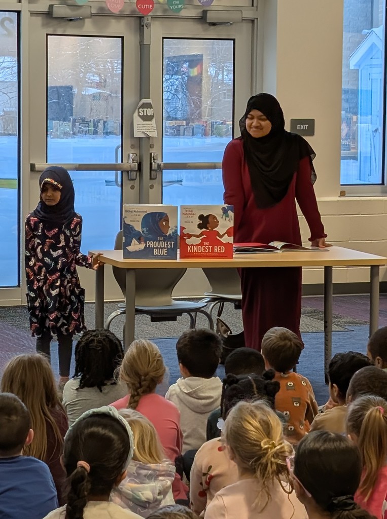 woman and child wearing hijabs talking to a group of students