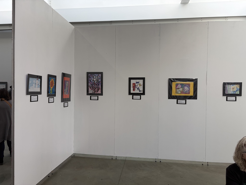multiple student paintings on a display wall