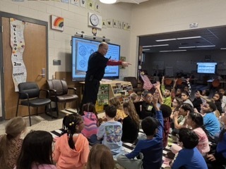 person teaching about scientific method in front of a Cleverboard. students raising hands