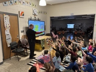 person teaching about scientific method in front of a Cleverboard. students raising hands
