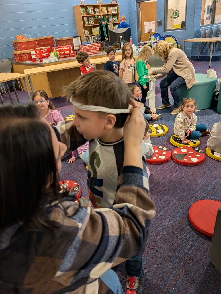 teacher creating a toilet paper headband for a student 