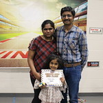 a child standing with adults with certificate 
