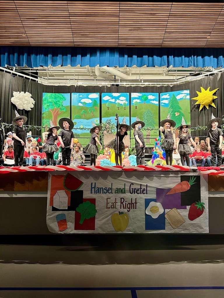 students on stage. some standing dressed as witches