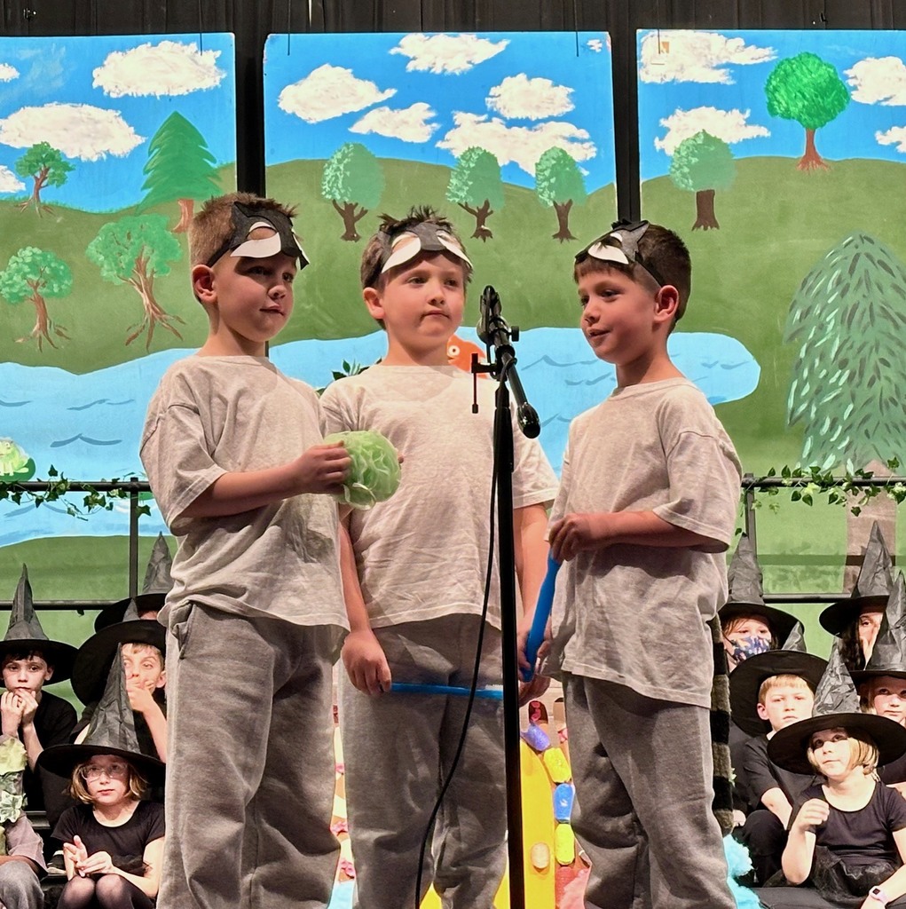 3 students standing by microphone on stage