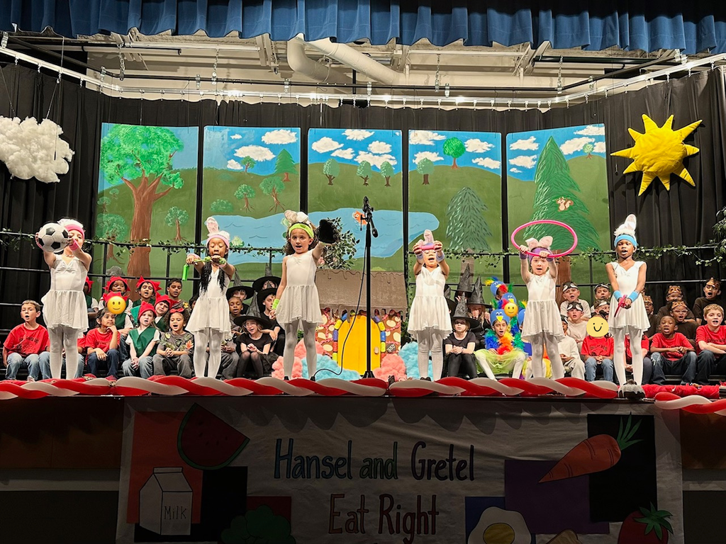 children standing on stage 6 wearing white costumes