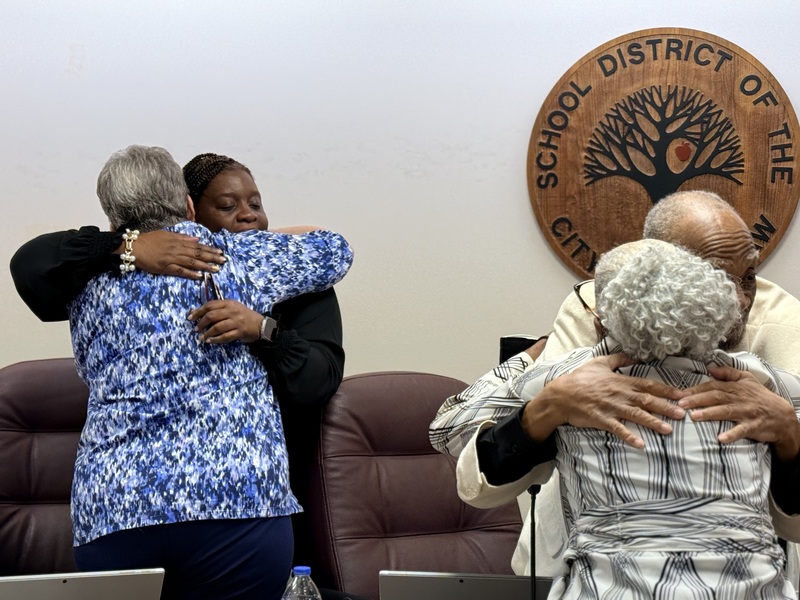 Members of Coach T's family hug school board members