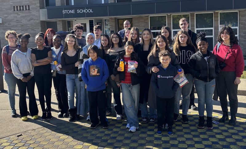 Students pose in front of school