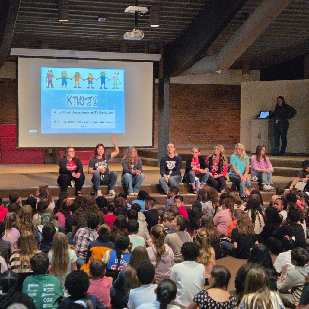 students look at staff on stage at assembly