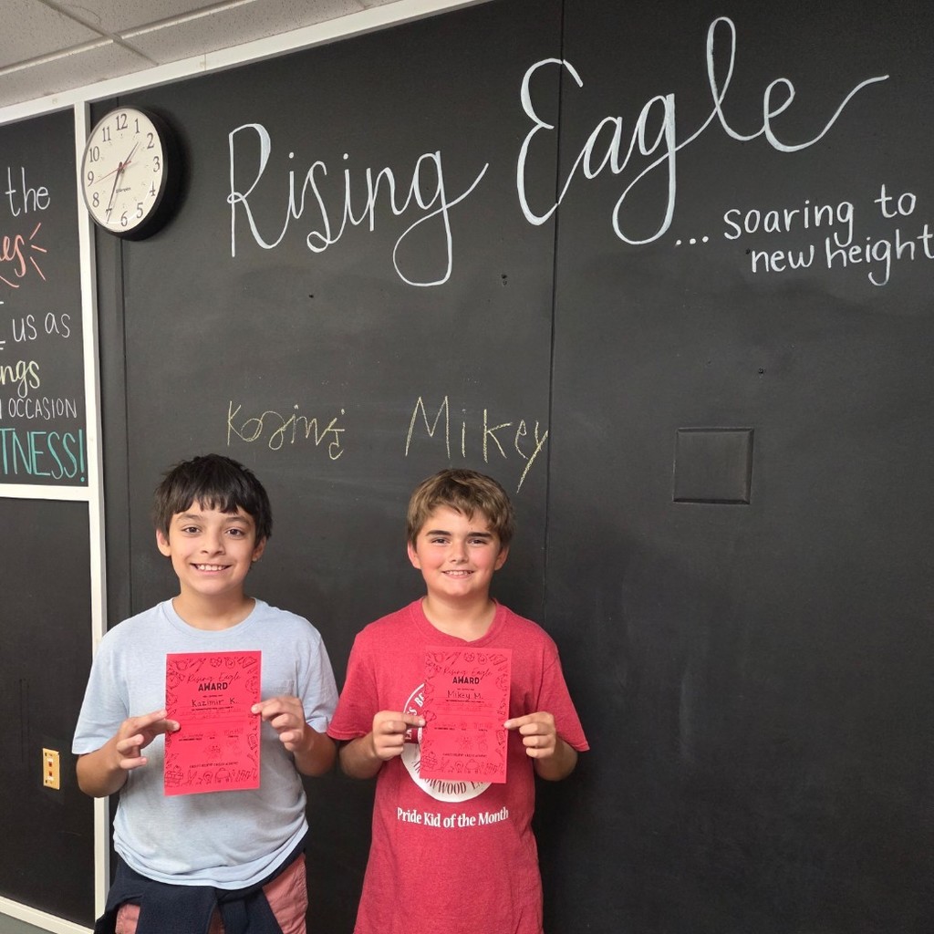 two boys smile with certificate under Rising Eagle sign