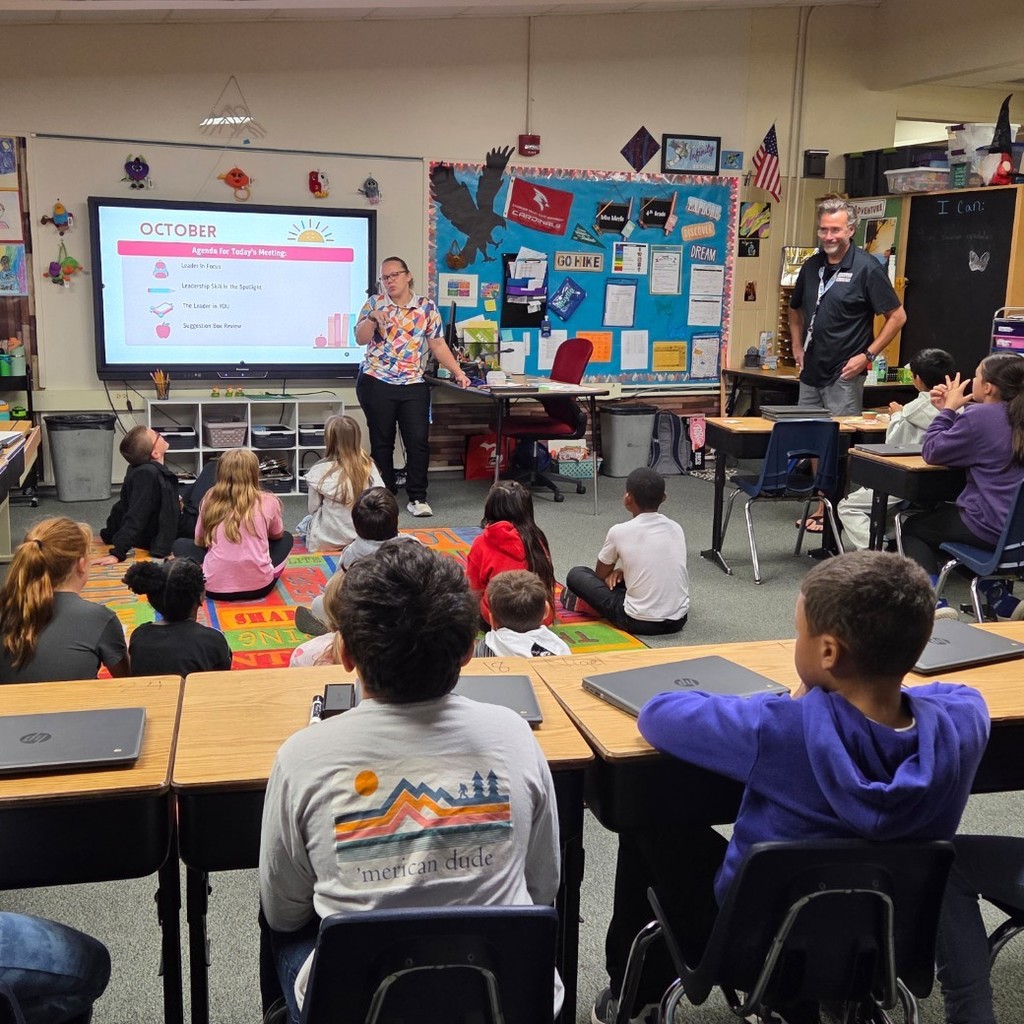 students sit and face teachers and screen