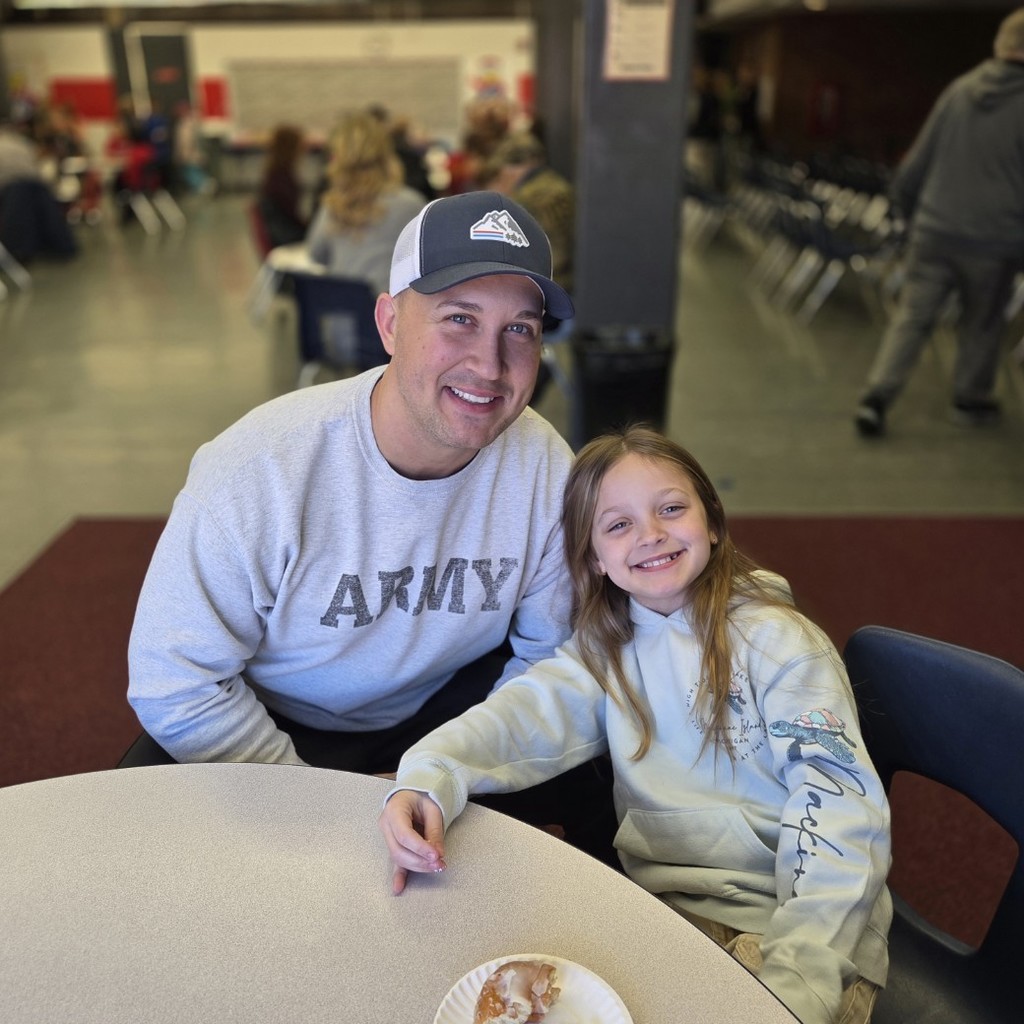 student smiles with her dad before assembly