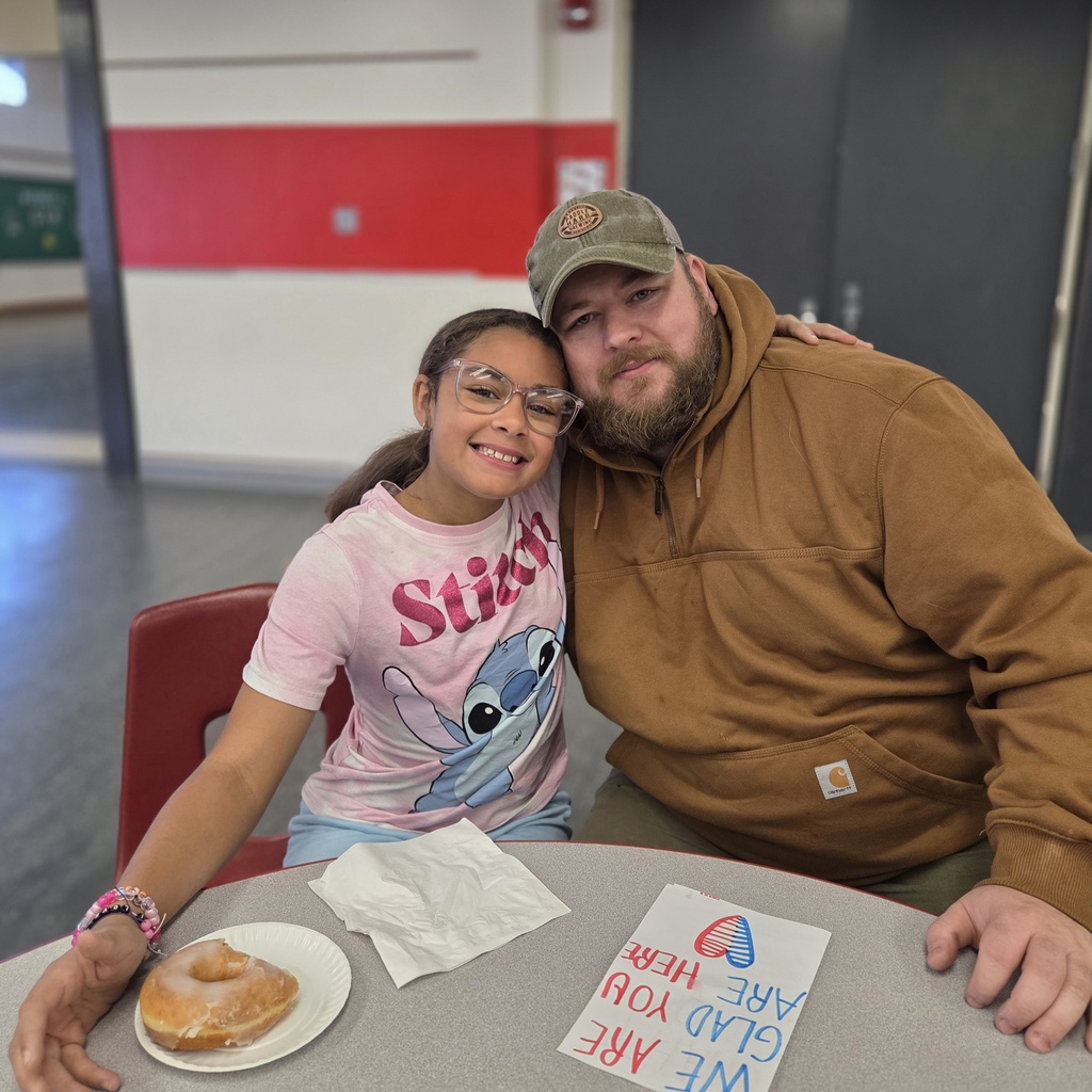 student smiles with veteran donut and card on table