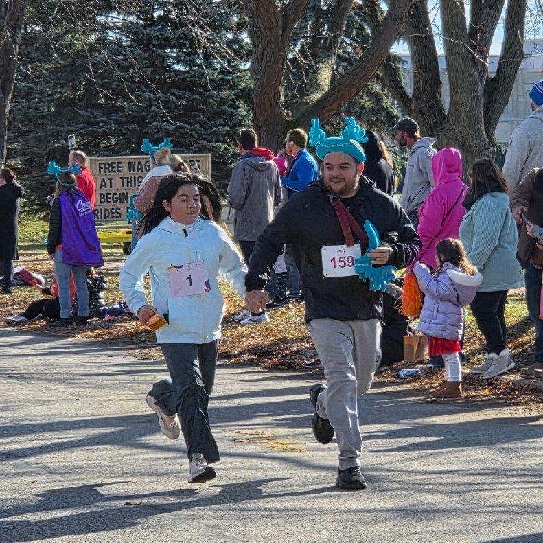 girl and dad hold hands running