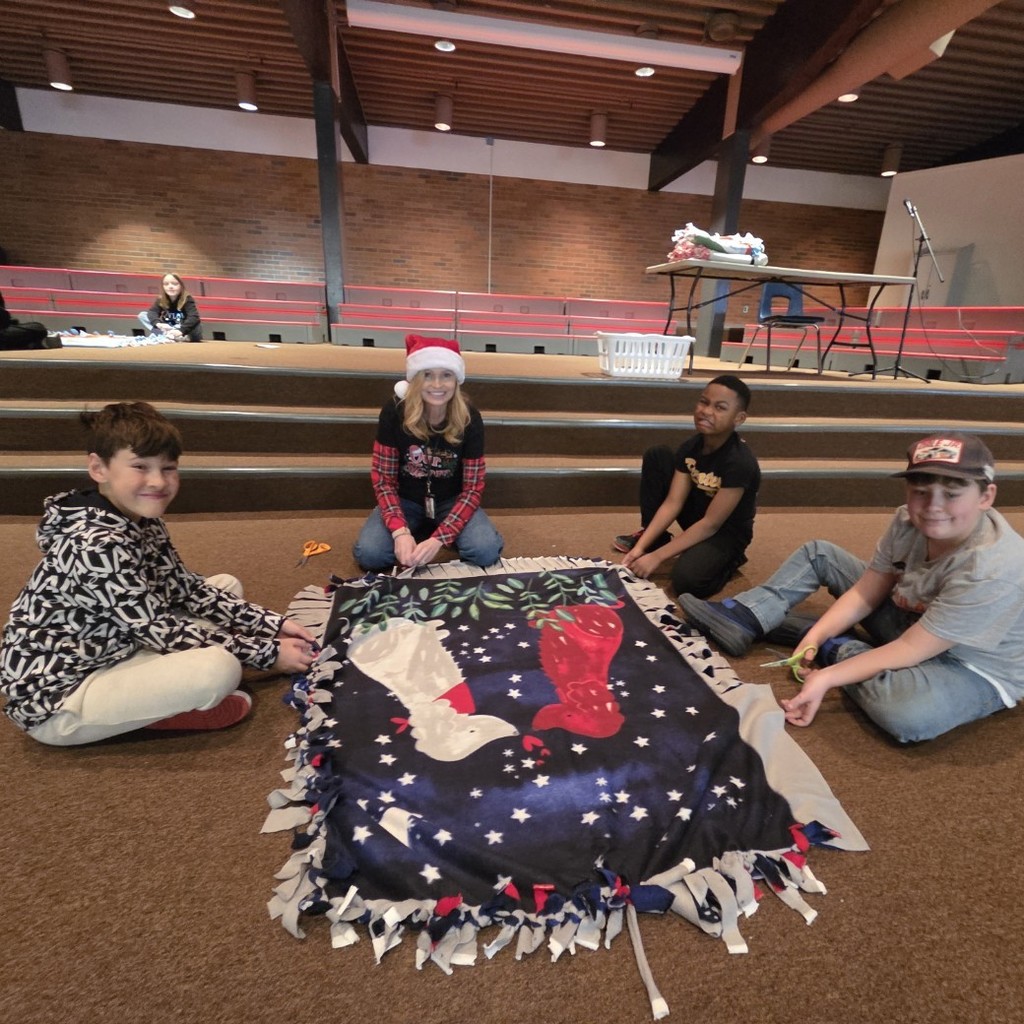 teacher and students cut and tie blanket