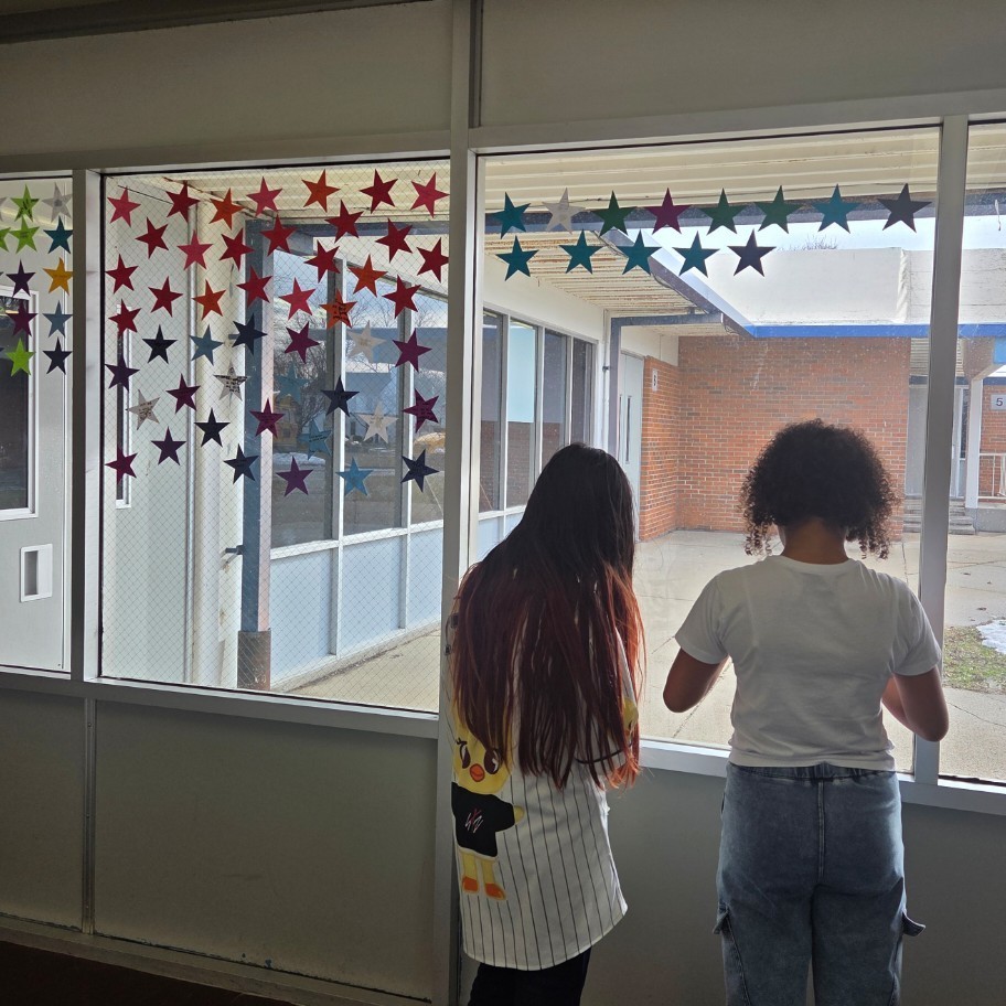 students tape up goals to window on paper stars 