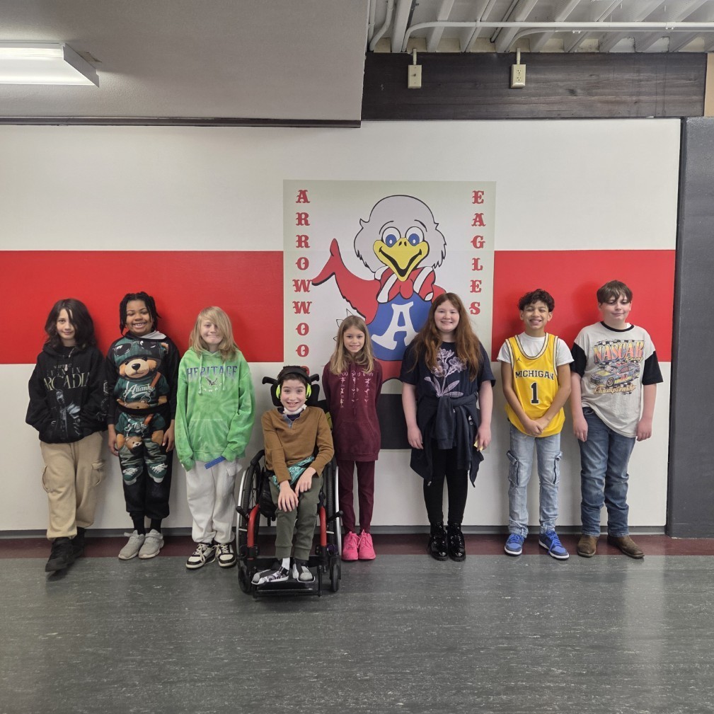 8 students stand and smile in front of Sparky the Eagle mascot
