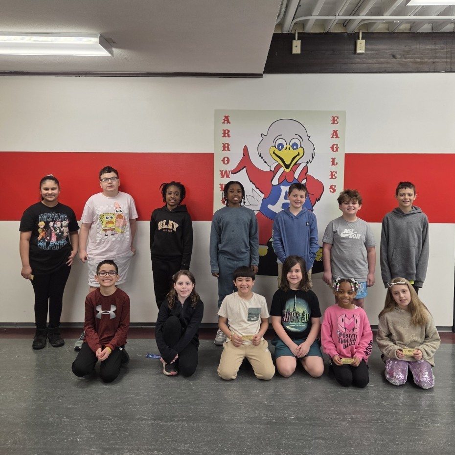 two rows of students smile by Sparky mascot