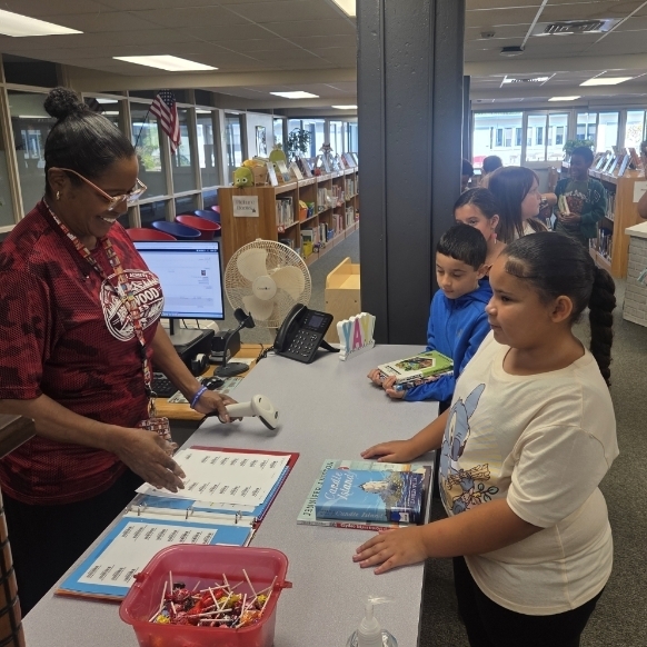 Librarian checks out books to students