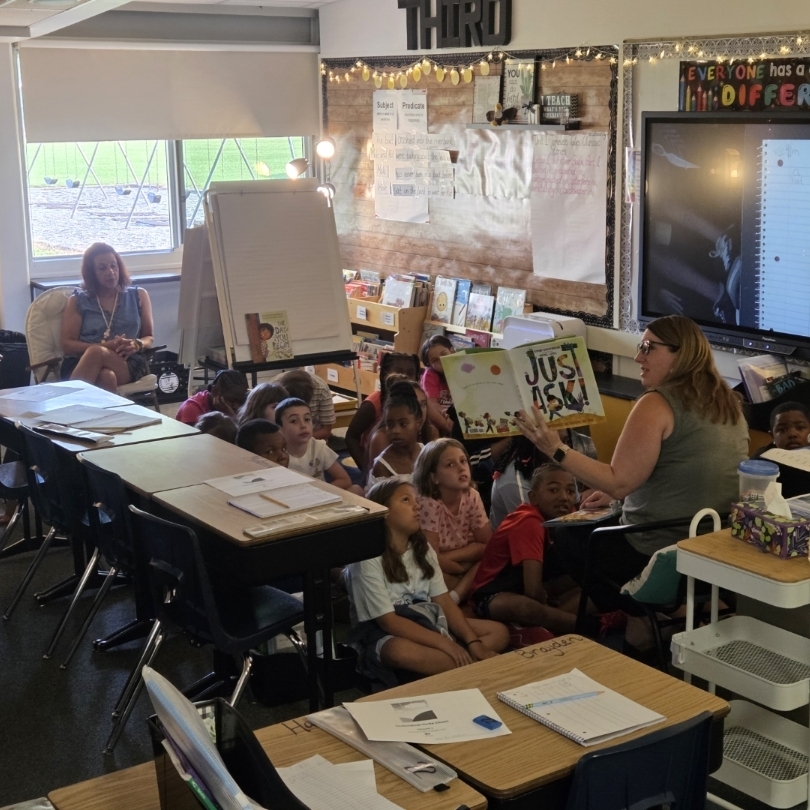 principal reads to students at carpet