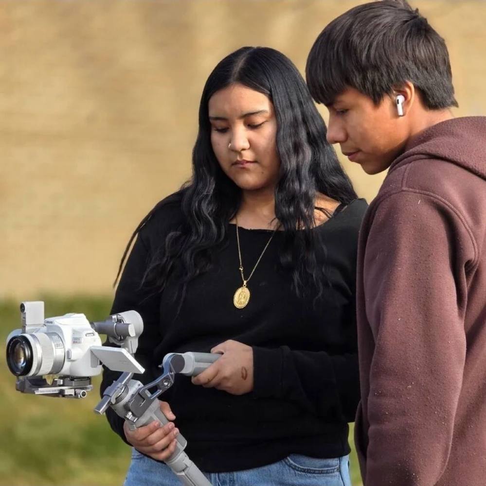 Two students holding a camera taking a video of the outside