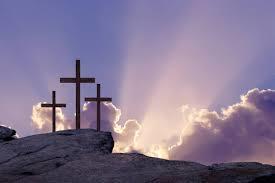 Three crosses on the hill with the sun poking through clouds