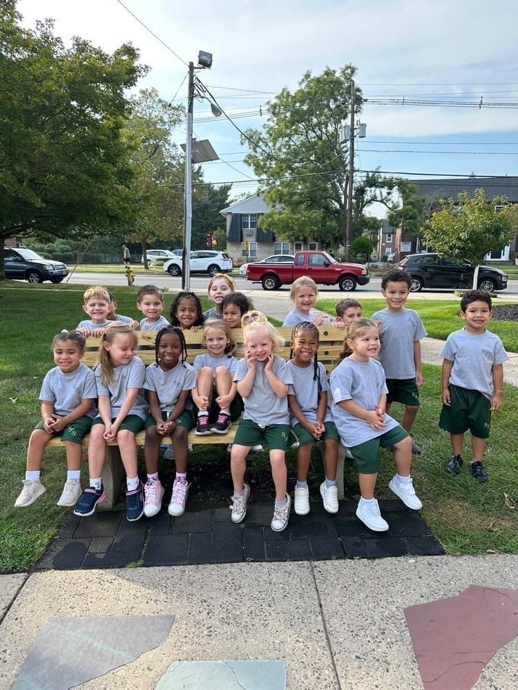 A group of Pre-School students sitting on a bench