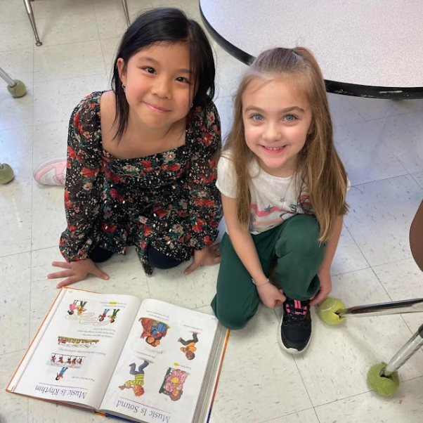 A 3rd grade and a Pre-school student reading to each other.