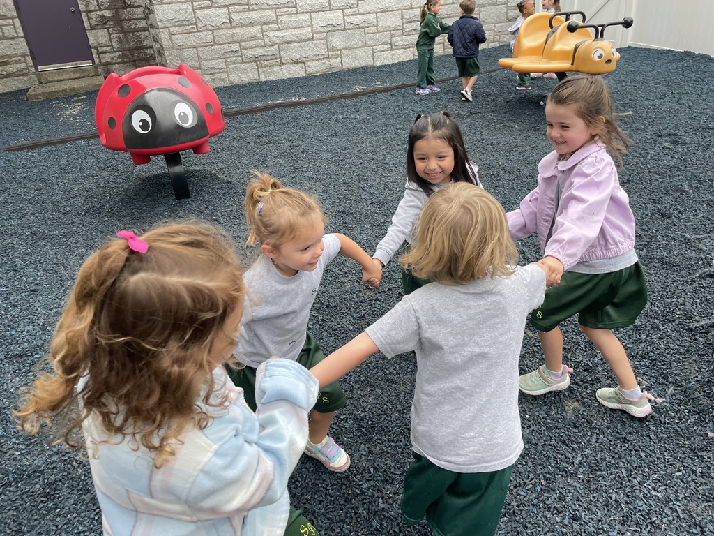 A group of pre-school age girls playing ring around the rosie