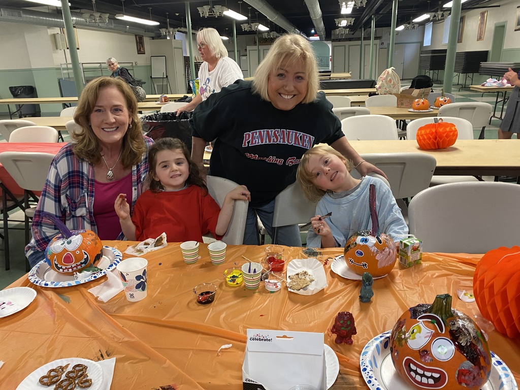 Two grandmothers with their Pre-school age granddaughters painting pumpkins for halloween