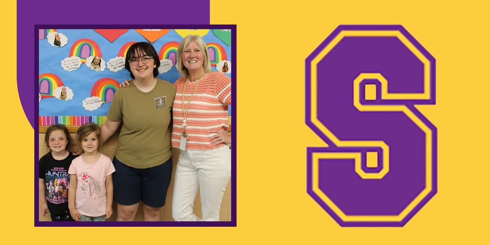 Photo of Parker, Mrs. Russo, and two pre K students smiling in front of a wall with rainbows made by the Pre K class
