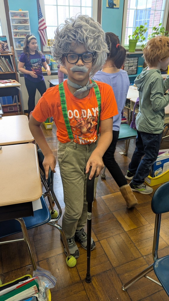 4th grade student dresses up with a gray wig, mustache, suspenders, and a cane.