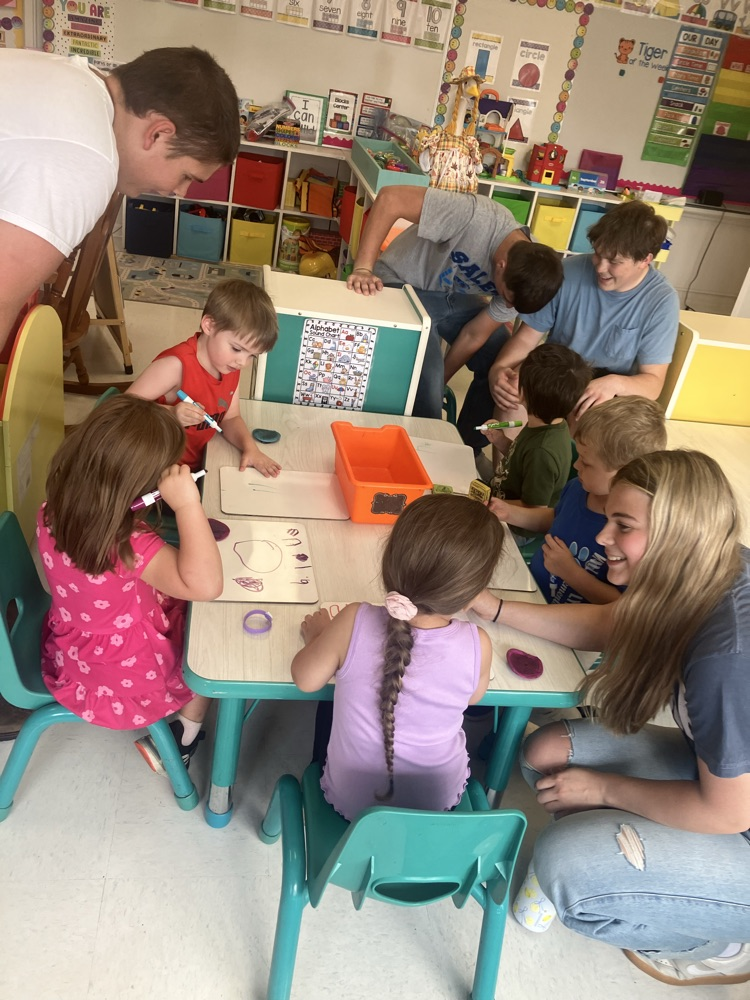 High school football players and a cheerleader visiting preschoolers.  