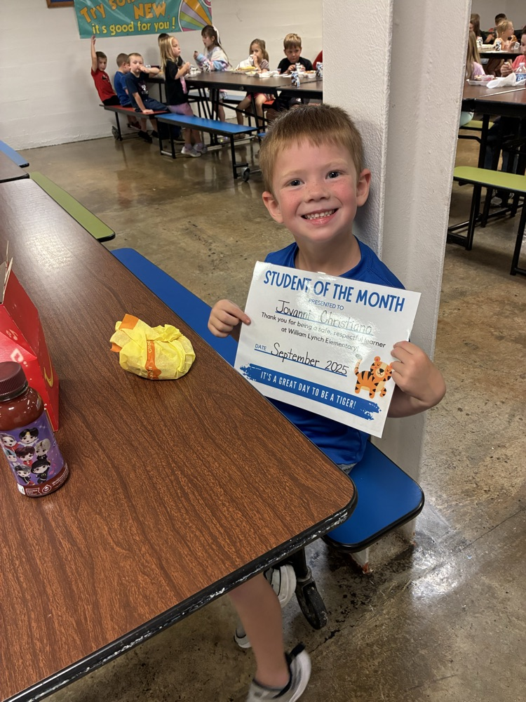 A kindergarten student of the month showing off his certificate