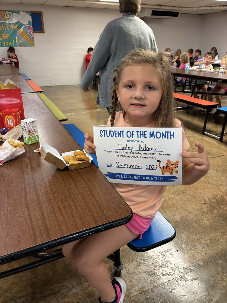 A kindergarten student of the month showing off her certificate