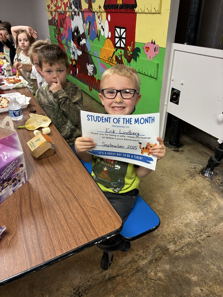 A kindergarten student of the month showing off his certificate