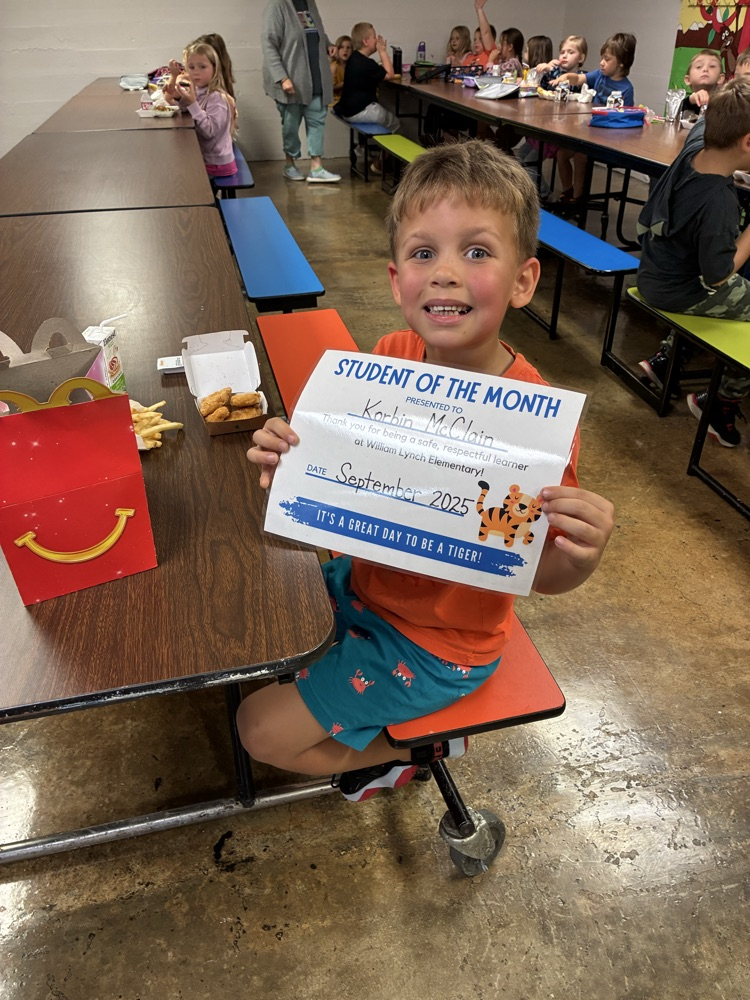 A kindergarten student of the month showing off his certificate