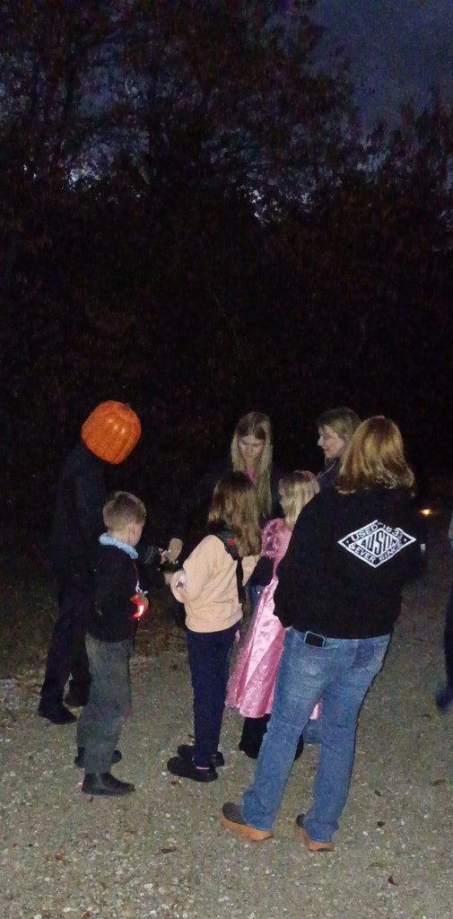 Student with a pumpkin head handing out candy to people