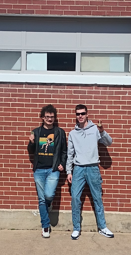 Two high school students in front of a brick wall