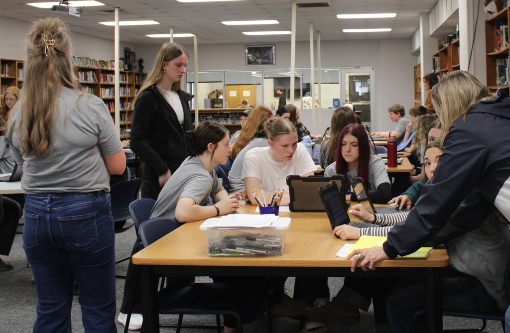 Students and teachers working together in groups on computers.