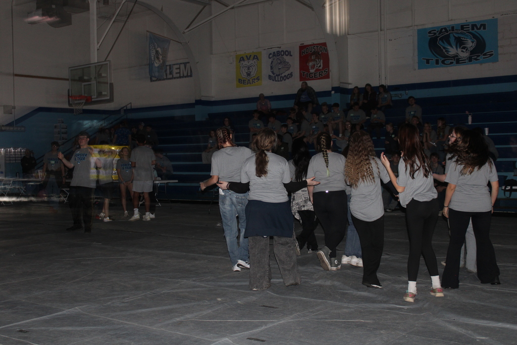 Group of students dancing in a dark gym. 
