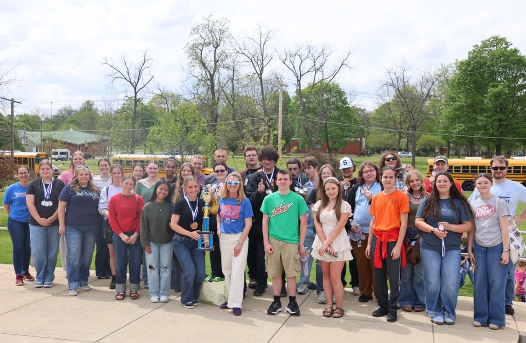 a group of high school students posing with sponsors and college staff with a first place trophy. 