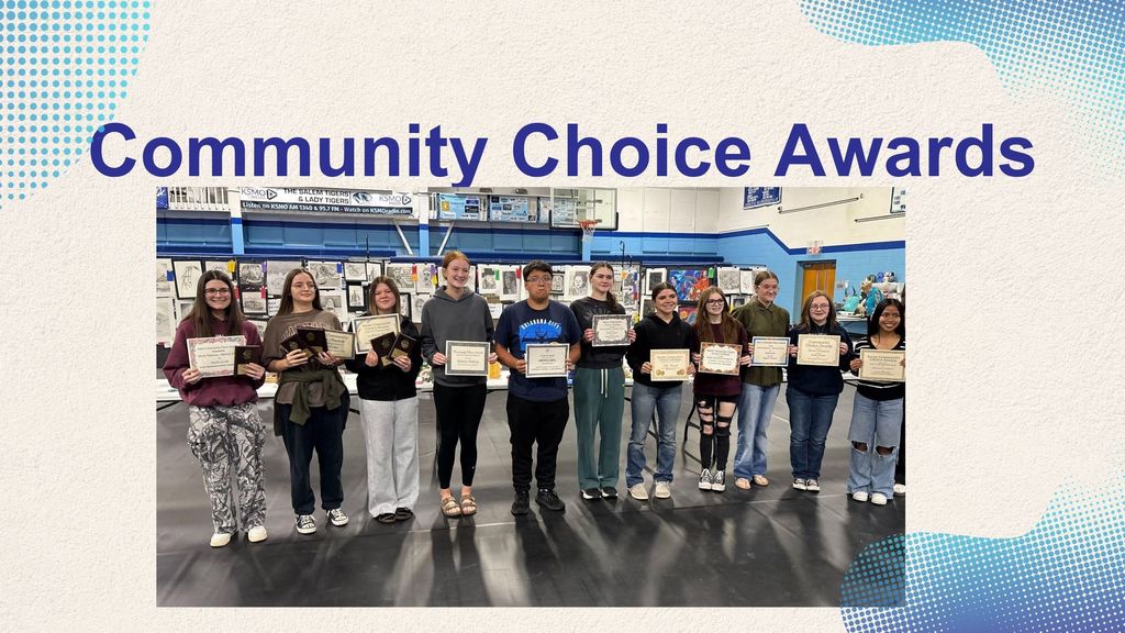 A group of young people stand in a line holding certificates and awards in front of a display of artwork.
