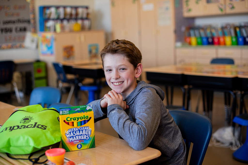 Boy sitting at a desk with Crayola washable markers in front of him